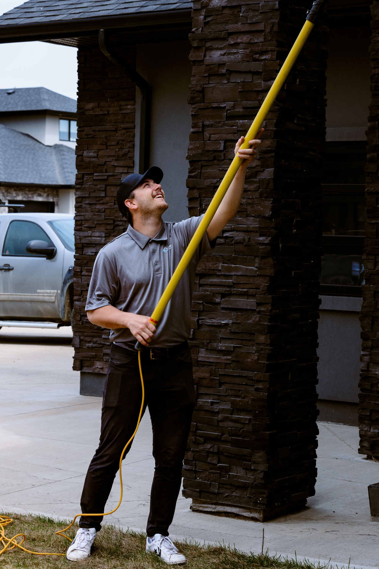 Technician cleaning exterior windows with an extension pole